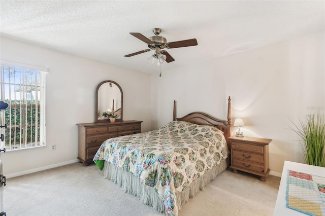 bedroom with ceiling fan, light carpet, and a textured ceiling