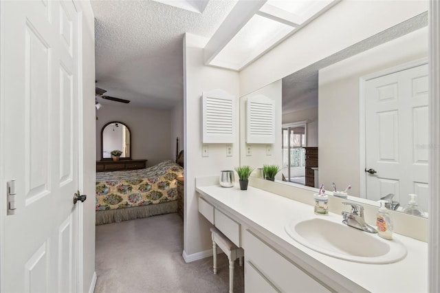 bathroom with vanity, ceiling fan, and a textured ceiling