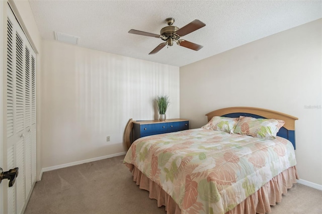 bedroom with ceiling fan, light colored carpet, a closet, and a textured ceiling