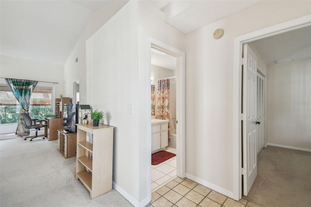 corridor featuring light tile patterned floors, baseboards, and light carpet