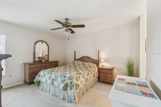 bedroom featuring a ceiling fan, light colored carpet, baseboards, and a textured ceiling