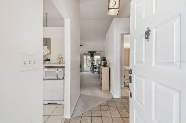 foyer entrance featuring light tile patterned floors, light colored carpet, and baseboards