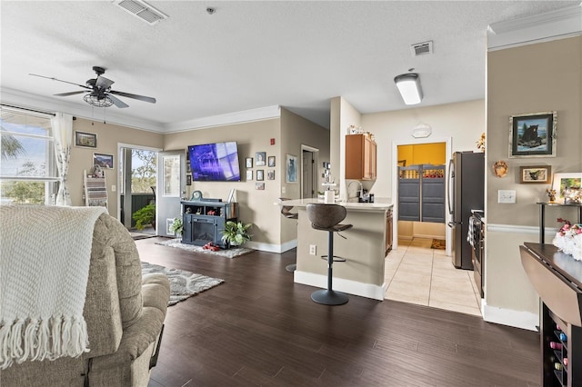 living room featuring sink, light hardwood / wood-style flooring, ornamental molding, and a textured ceiling