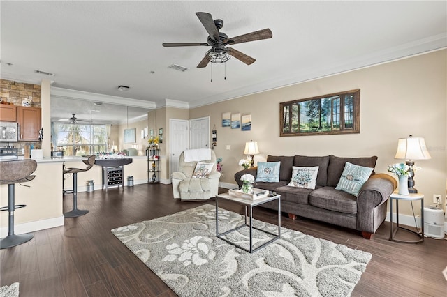 living room featuring ornamental molding, dark wood-style flooring, visible vents, and ceiling fan