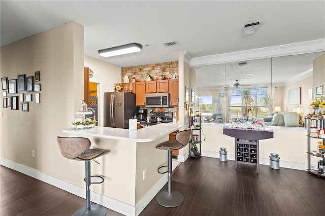 kitchen featuring a kitchen bar, dark wood-type flooring, kitchen peninsula, and appliances with stainless steel finishes