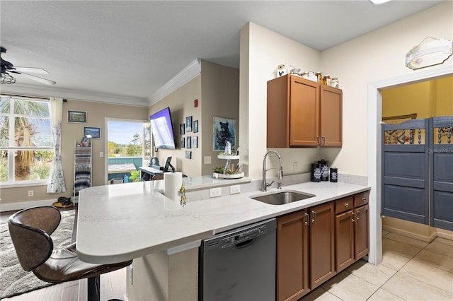 kitchen featuring black dishwasher, light stone counters, a peninsula, a kitchen bar, and a sink