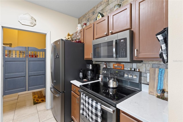 kitchen with appliances with stainless steel finishes, decorative backsplash, and light tile patterned floors