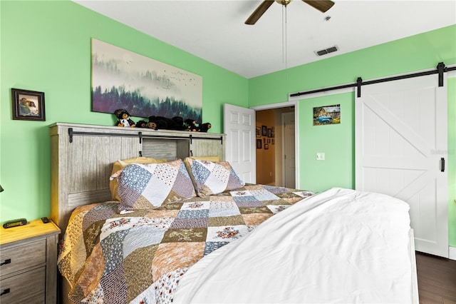 bedroom featuring dark wood-type flooring, ceiling fan, and a barn door