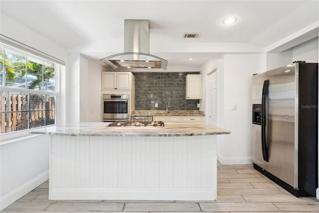 kitchen featuring visible vents, decorative backsplash, appliances with stainless steel finishes, island exhaust hood, and wood finish floors