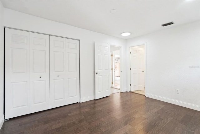 unfurnished bedroom with dark hardwood / wood-style floors and a closet