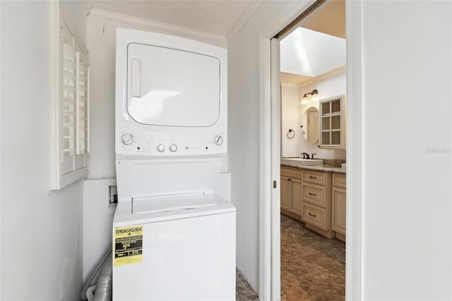 laundry area featuring stacked washer and dryer, ornamental molding, and sink