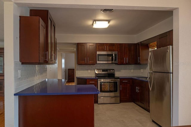 kitchen with tasteful backsplash, appliances with stainless steel finishes, and kitchen peninsula