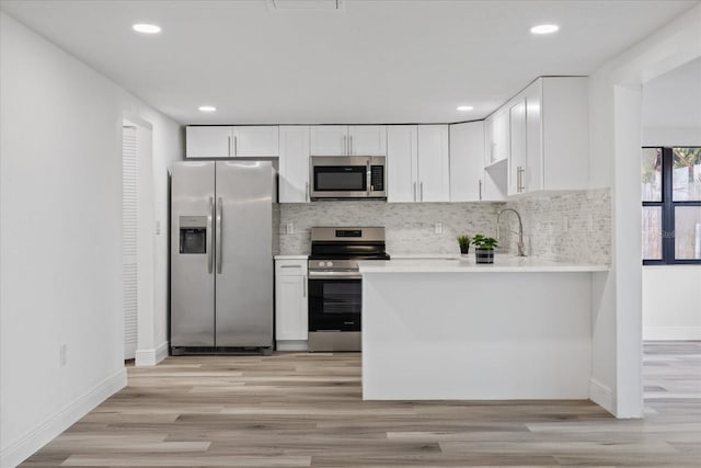 kitchen with backsplash, stainless steel appliances, light wood-type flooring, and white cabinets