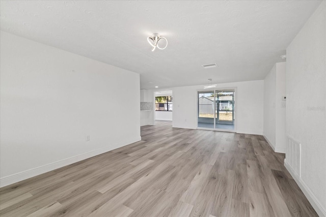 unfurnished living room with light hardwood / wood-style flooring and a textured ceiling