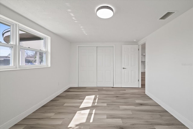 unfurnished bedroom with a closet and light wood-type flooring