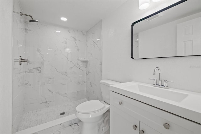 bathroom with vanity, toilet, and a tile shower