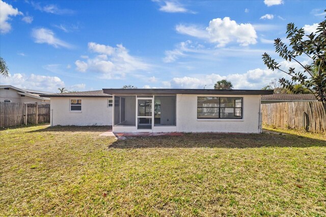 rear view of house featuring a sunroom and a yard