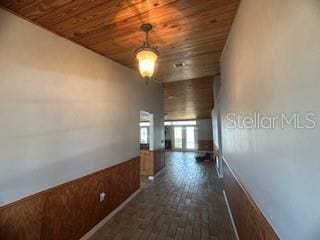 corridor with wood ceiling, dark hardwood / wood-style flooring, and wood walls