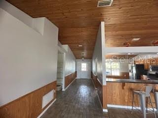 kitchen featuring dark wood-type flooring, a breakfast bar, stainless steel appliances, wooden ceiling, and kitchen peninsula