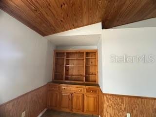 bar with vaulted ceiling, wooden ceiling, and wood walls