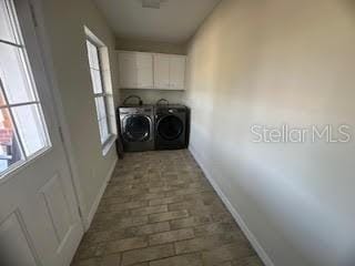 clothes washing area with cabinets and washer and dryer