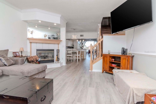 living room featuring ornamental molding, a tile fireplace, and light wood-type flooring