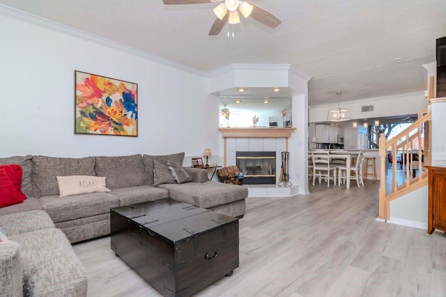 living room featuring crown molding, a fireplace, and light hardwood / wood-style floors