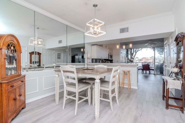 dining area featuring crown molding, ceiling fan with notable chandelier, and light hardwood / wood-style floors