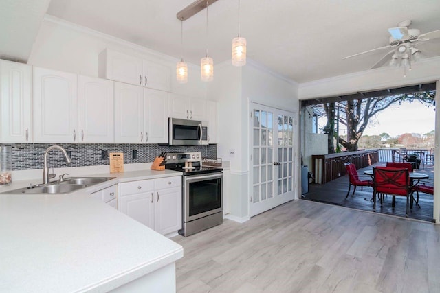 kitchen with pendant lighting, sink, white cabinets, stainless steel appliances, and crown molding