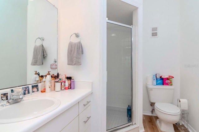 bathroom featuring hardwood / wood-style flooring, toilet, vanity, and a shower with shower door