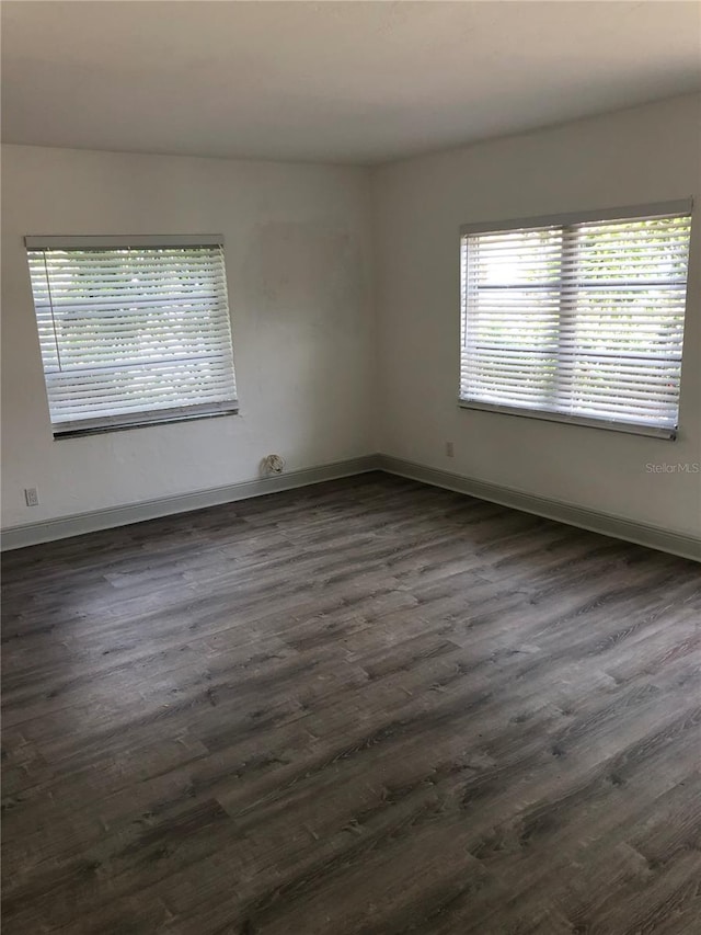 spare room featuring plenty of natural light and dark hardwood / wood-style floors