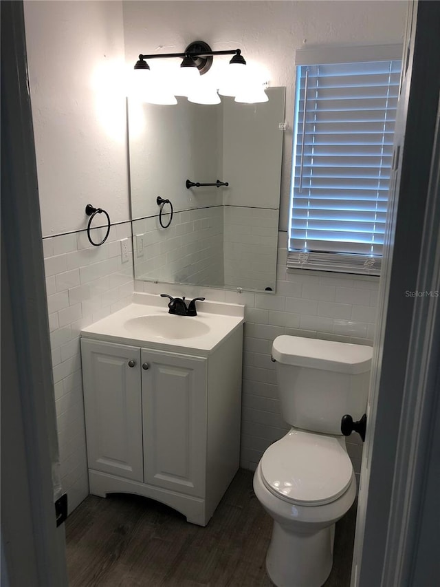 bathroom with hardwood / wood-style floors, vanity, tile walls, and toilet