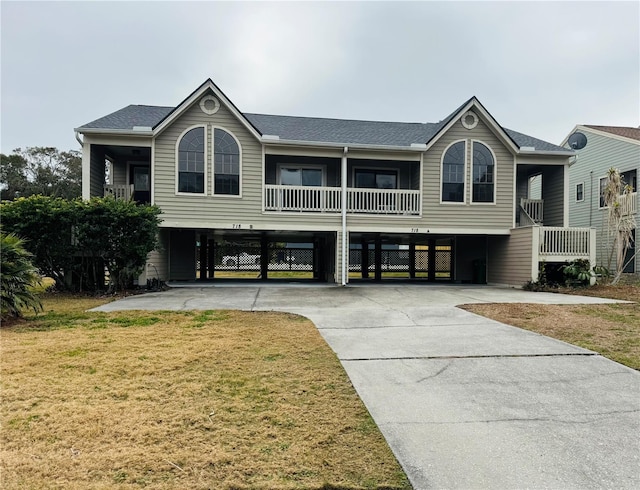 view of front of home with a carport, a balcony, and a front yard