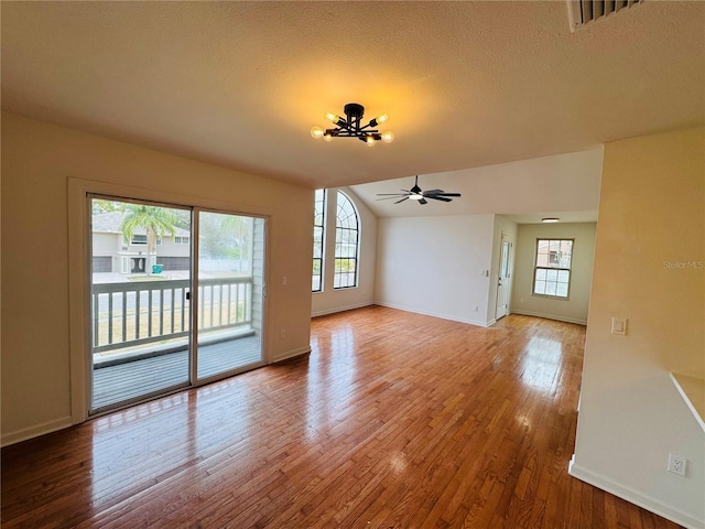 unfurnished living room featuring lofted ceiling, ceiling fan, a wealth of natural light, and wood-type flooring