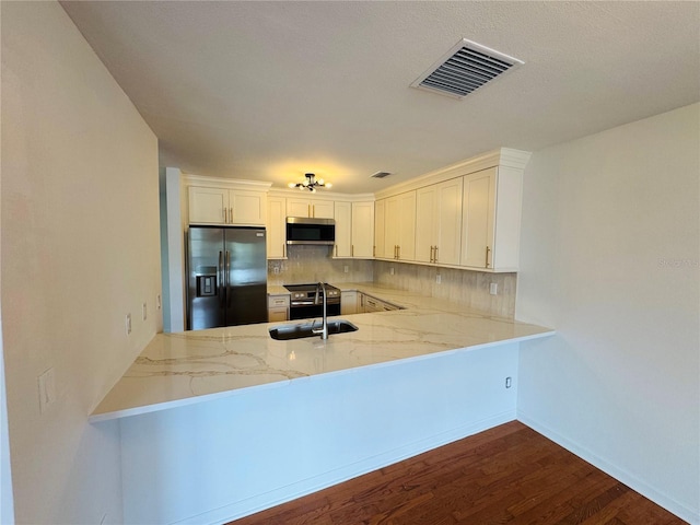 kitchen with white cabinetry, sink, kitchen peninsula, and black refrigerator with ice dispenser