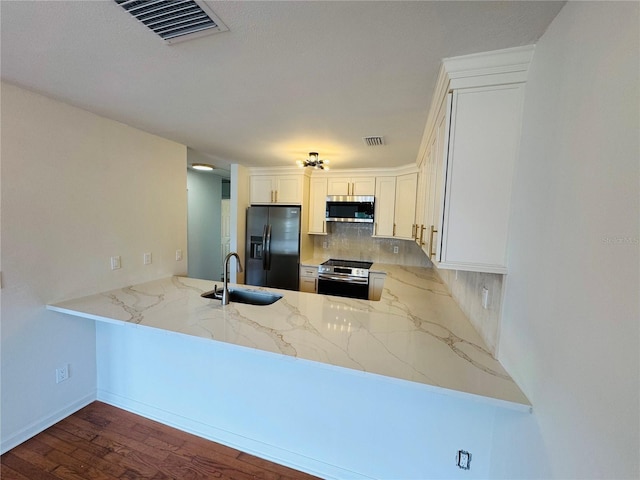 kitchen with white cabinetry, sink, stainless steel appliances, and kitchen peninsula