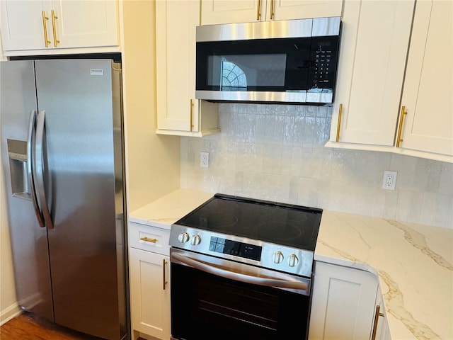 kitchen with light stone counters, backsplash, white cabinetry, and appliances with stainless steel finishes