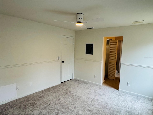 spare room featuring light colored carpet, electric panel, and ceiling fan