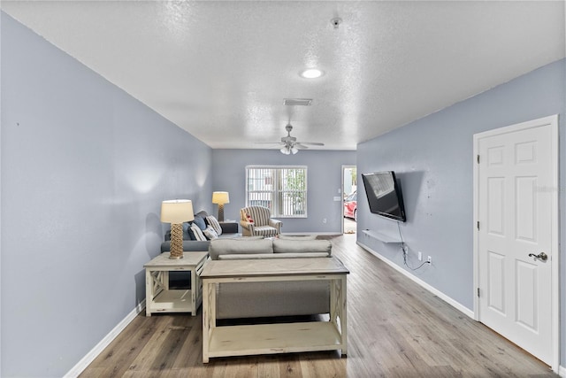 living room featuring ceiling fan, wood-type flooring, and a textured ceiling