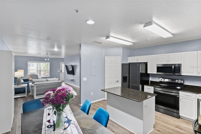 kitchen with white cabinetry, appliances with stainless steel finishes, a center island, and light hardwood / wood-style flooring