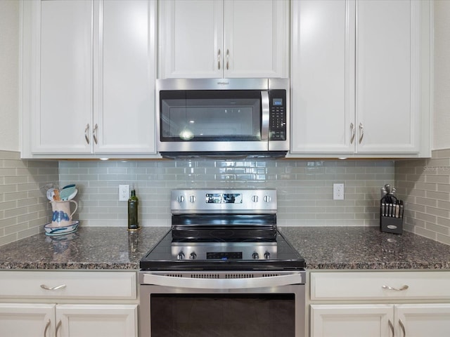 kitchen featuring appliances with stainless steel finishes, dark stone counters, and white cabinets