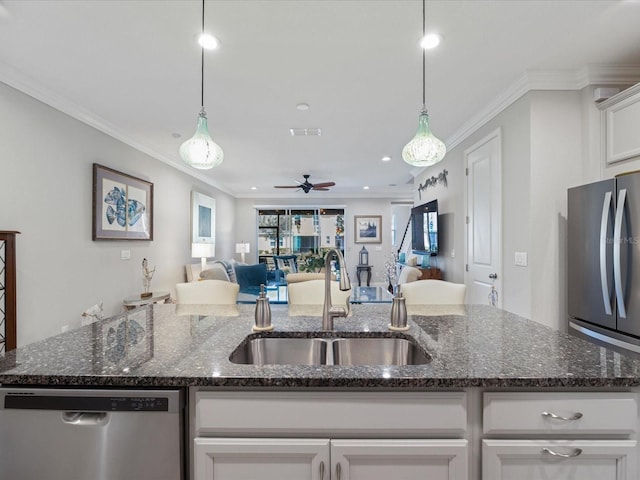 kitchen with sink, white cabinetry, dark stone countertops, stainless steel appliances, and an island with sink