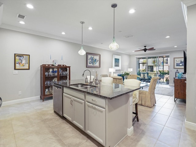 kitchen with sink, dishwasher, hanging light fixtures, an island with sink, and dark stone counters