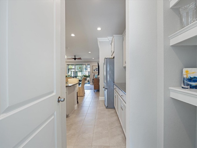 kitchen featuring stone countertops, light tile patterned floors, stainless steel refrigerator, ceiling fan, and white cabinets