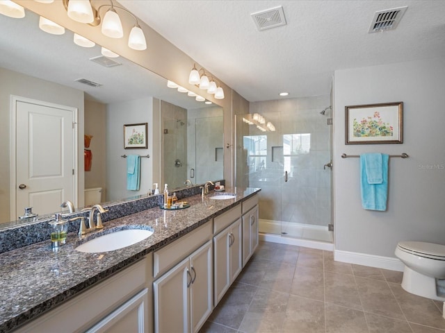 bathroom featuring toilet, a textured ceiling, vanity, a shower with door, and tile patterned flooring