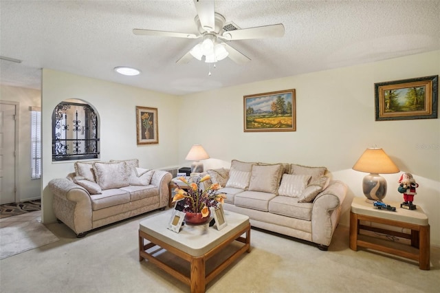 living room featuring ceiling fan, light carpet, and a textured ceiling