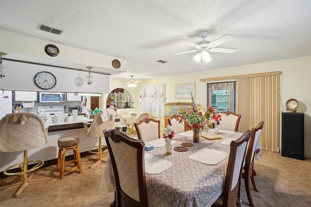 dining room featuring light carpet, a textured ceiling, and ceiling fan