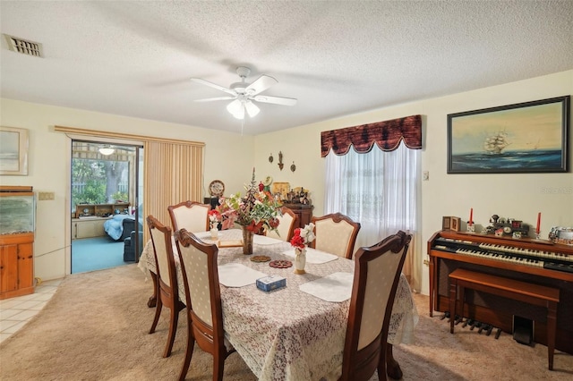 carpeted dining area featuring ceiling fan, plenty of natural light, and a textured ceiling