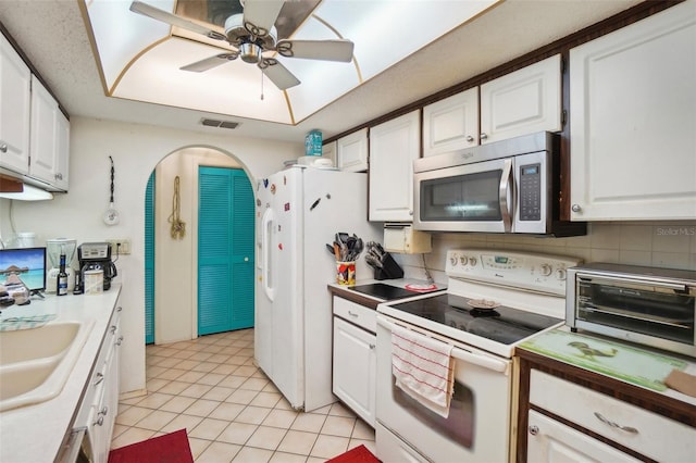 kitchen featuring sink, white appliances, white cabinets, ceiling fan, and backsplash