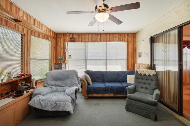 living room featuring carpet, ceiling fan, and wood walls